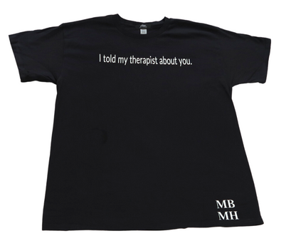 Short sleeve black colored t-shirt with white vinyl lettering with phrase “I told my therapist about you.”